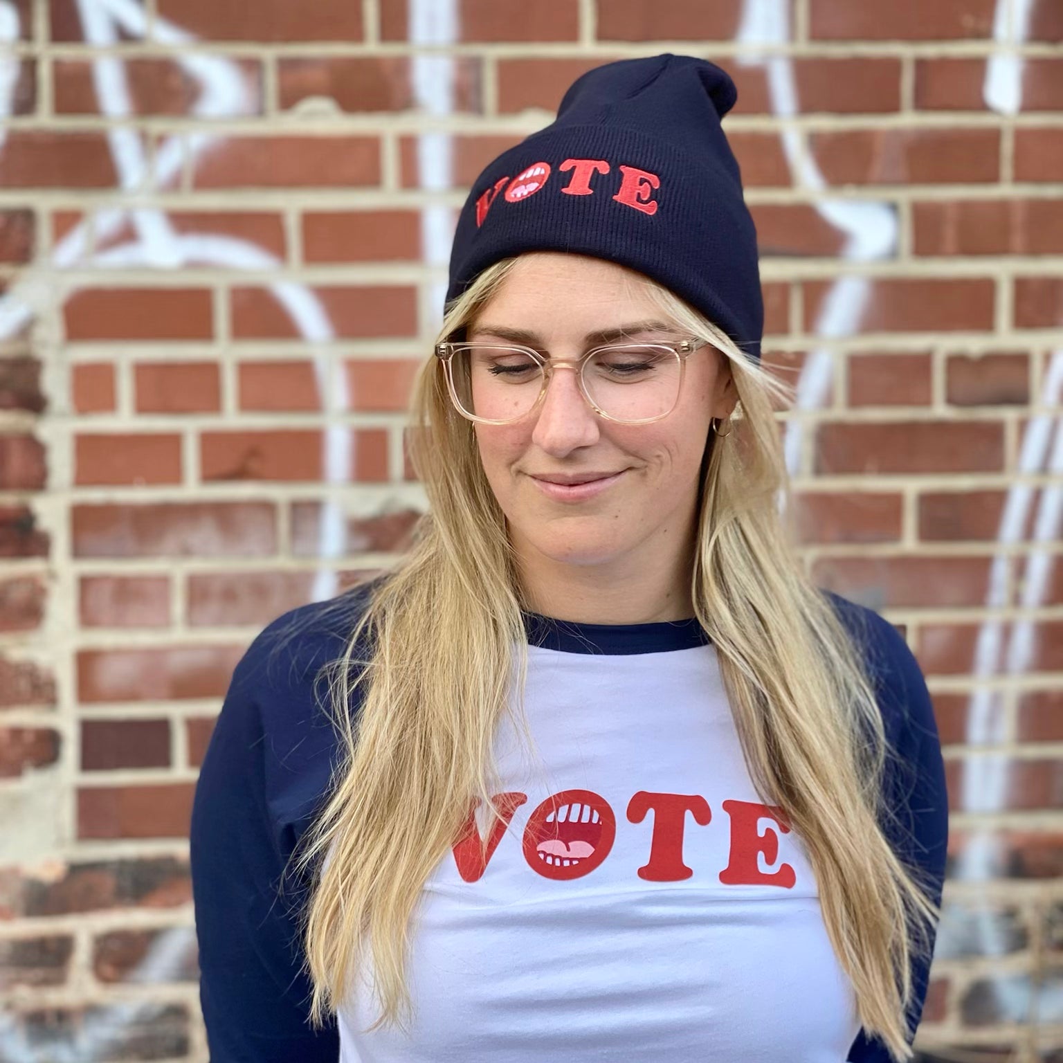 Blonde woman wearing vote beanie and vote raglan