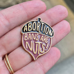 Load image into Gallery viewer, Acorn shaped enamel pin with "abortion bans are nuts" design