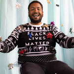 Load image into Gallery viewer, A person wearing the Black Lives Matter Holiday Sweater. There is an ice blue background and bows around them.