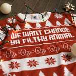 Load image into Gallery viewer, A flat lay of the We Want Change Holiday Sweater. There are colorful holiday lights, ornaments, and bows around it.
