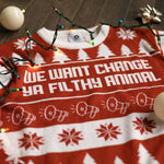 Load image into Gallery viewer, A flat lay of the We Want Change Holiday Sweater. There are colorful holiday lights, ornaments, and bows around it.
