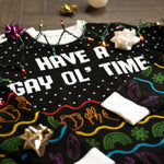 Load image into Gallery viewer, A flat lay of the Have A Gay Ol' Time Holiday Sweater. There are colorful holiday lights, bows, and ornaments around it.