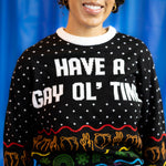 Load image into Gallery viewer, A person wearing the Have A Gay Ol' Time Holiday Sweater. There is a blue background.