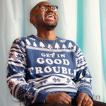 Load image into Gallery viewer, A person wearing the Get In Good Trouble Holiday Sweater. There is an ice blue background.