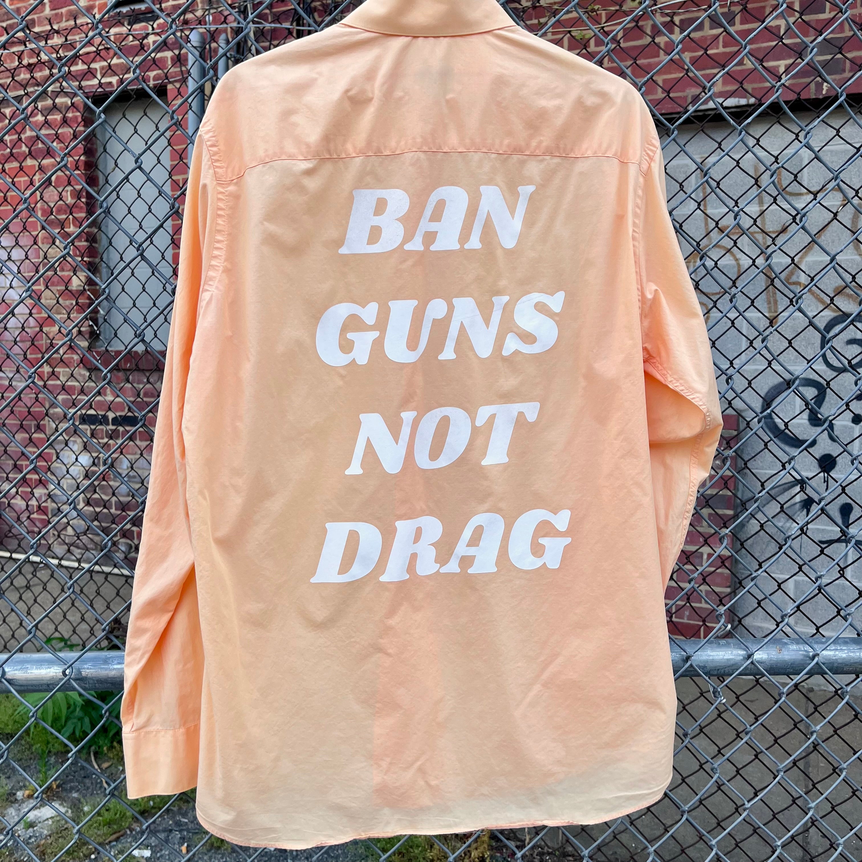 Orange up cycled button down with "Ban Guns Not Drag" printed across the back in a 70s font.