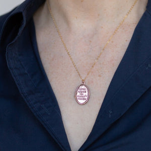 "Human Rights are Women's rights" HRC quote bronze medallion necklace worn by a woman in a navy button down
