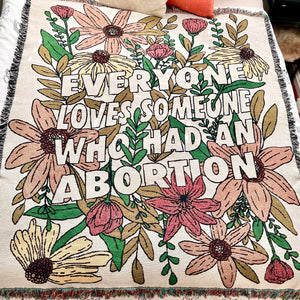 Cotton throw blanket with fringe and floral design with "Everyone Loves Someone Who Had An Abortion"