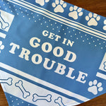 Load image into Gallery viewer, Flat lay close up of blue Dog Bandana with &quot;Get In Good Trouble&quot; design with pay prints and bones
