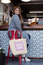 Load image into Gallery viewer, Stop Asian Hate tote bag on chair with person sitting.
