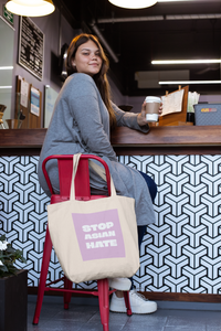 Stop Asian Hate tote bag on chair with person sitting.