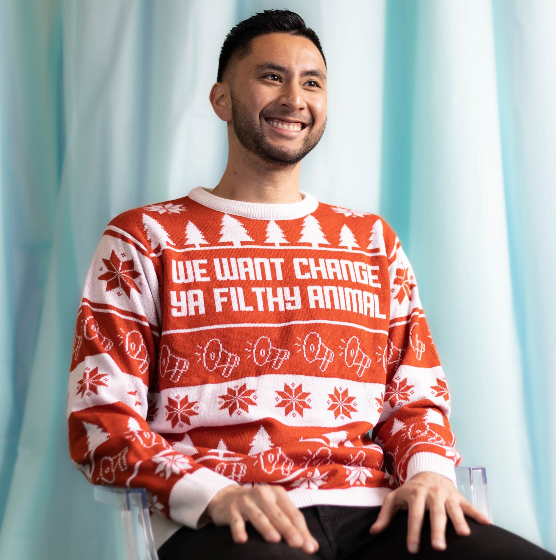 A person wearing the We Want Change Holiday Sweater. There is an ice blue background.