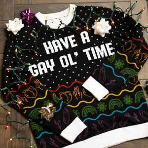 A flat lay of the Have A Gay Ol' Time Holiday Sweater. There are colorful holiday lights, bows, and ornaments around it.