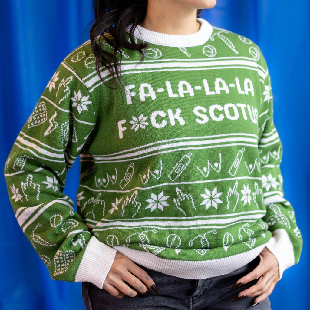 Photo of a person wearing the Fa-La-La-La F*ck SCOTUS Holiday Sweater. There is  a blue background.