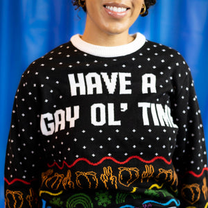 A person wearing the Have A Gay Ol' Time Holiday Sweater. There is a blue background.