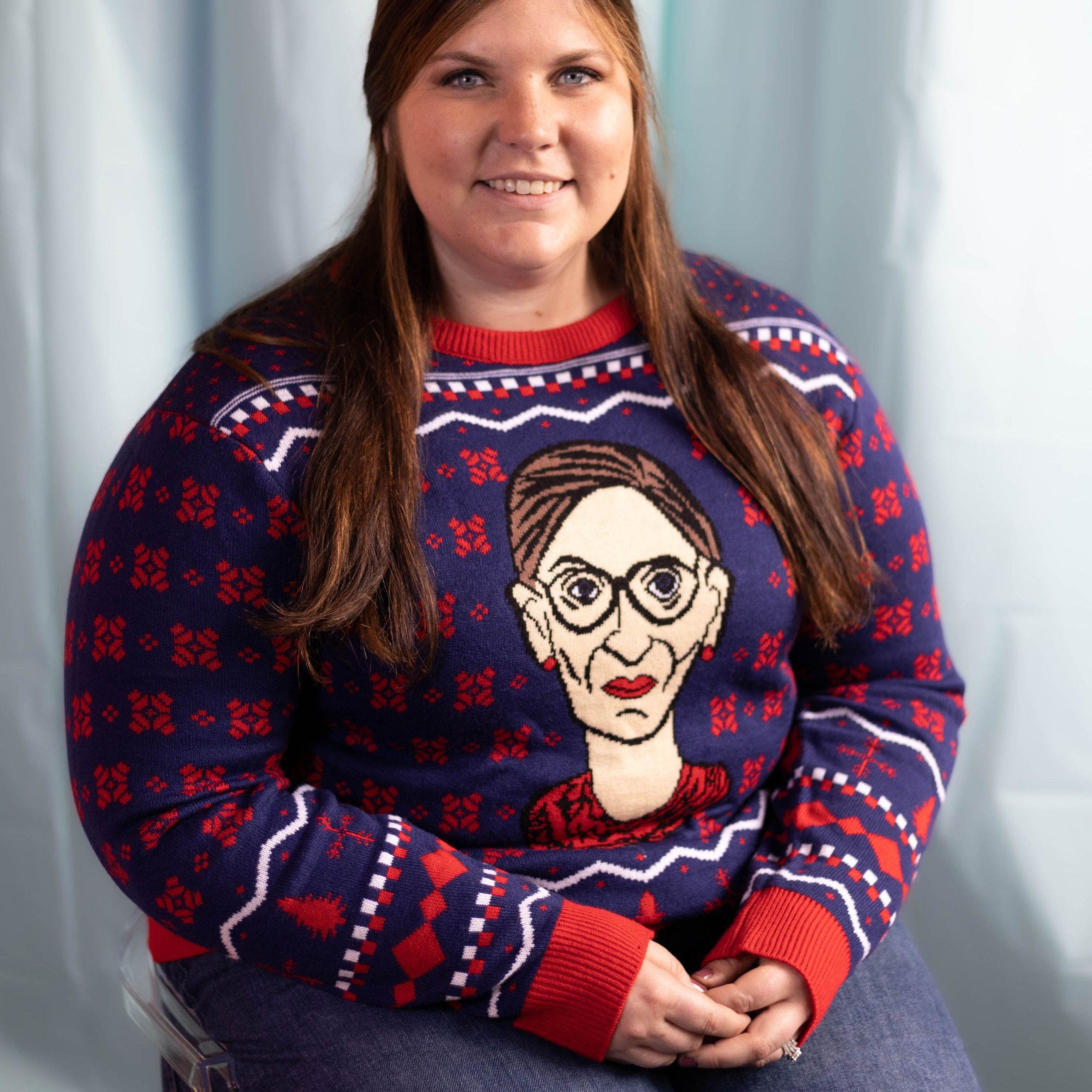 A person wearing the RBG Holiday Sweater. There is an ice blue background.