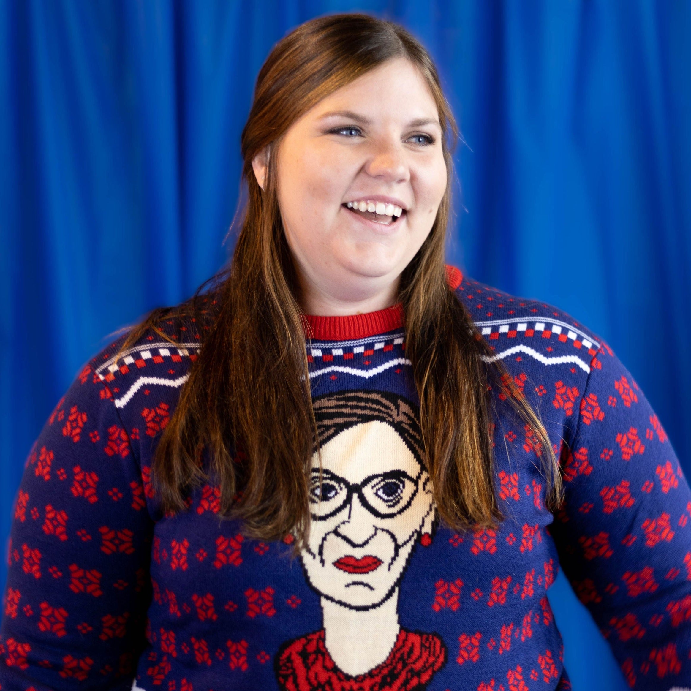 A person wearing the RBG Holiday Sweater. There is a blue background.