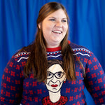 Load image into Gallery viewer, A person wearing the RBG Holiday Sweater. There is a blue background.
