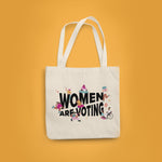 Load image into Gallery viewer, Yellow background with a natural canvas tote with &quot;Women Are Voting&quot; in black with inclusive femme figures surrounding.

