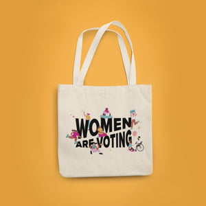 Yellow background with a natural canvas tote with "Women Are Voting" in black with inclusive femme figures surrounding.