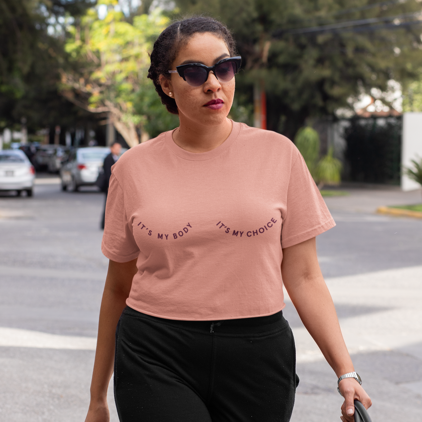 A photo of a woman wearing the It's My Body It's My Choice Boxy Crop. It's a dusty pink color shirt with a burgundy print.
