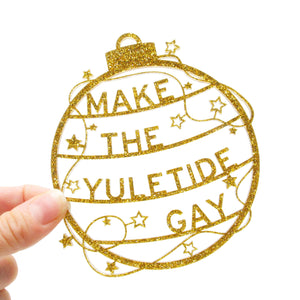 Gold, sparkly laser cut holiday ornament that reads "Make The Yuletide Gay"