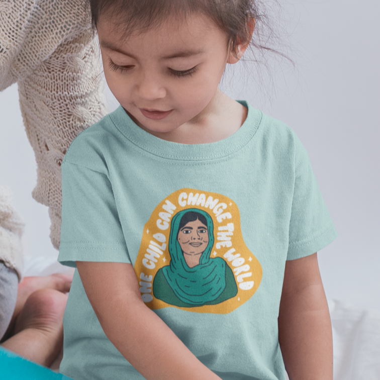 Toddler wearing Malala t-shirt from The Outrage sitting next to an adult while they read a picture book.