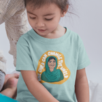 Load image into Gallery viewer, Toddler wearing Malala t-shirt from The Outrage sitting next to an adult while they read a picture book.
