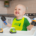 Load image into Gallery viewer, Small child in a highchair wears a yellow silicon bib with pocket and green design &quot;Squash The Patriarchy&quot;
