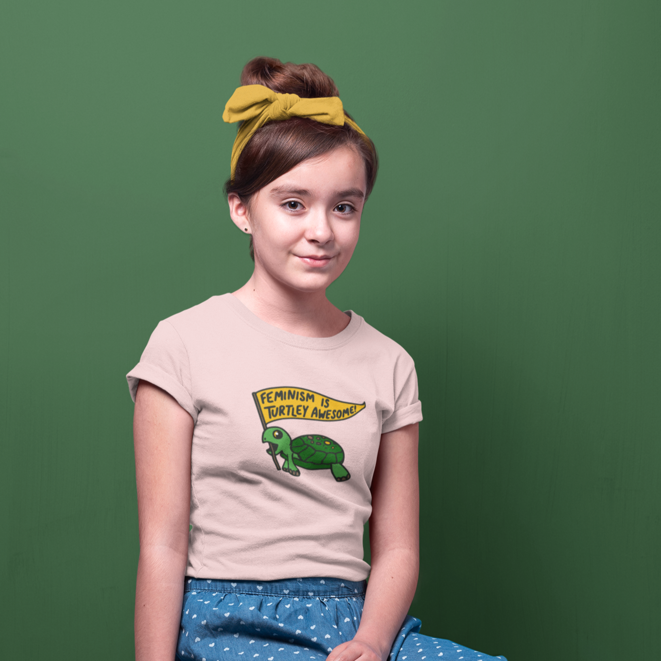 girl with headband wearing peach shirt with "Feminism Is Turtley Awesome" design