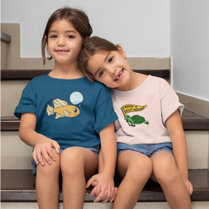 girls sit on the stairs holding hands, one in a teal shirt with "climate justice is fantastic" design and one in a peach "feminism is turtley awesome" design